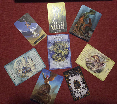 Color photo of eight oracle cards from a mixed deck made from E. Lubanko's Tarot, Paolo Barbieri's Night Fairies Oracle, and Jody Bergasma's Magical Times Empowerment cards. 7 cards are arranged in a circle, with the 8th in the middle. Reading the cards clockwise: Seven of Wands, Discernment, Union Reversed, Three of Wands Reversed, Progress, Pilgrimage Reversed, Ten of Wands. In the center is the card: Integrity.